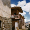 Woman and llama walk past Spanish homes built on top of Incan walls